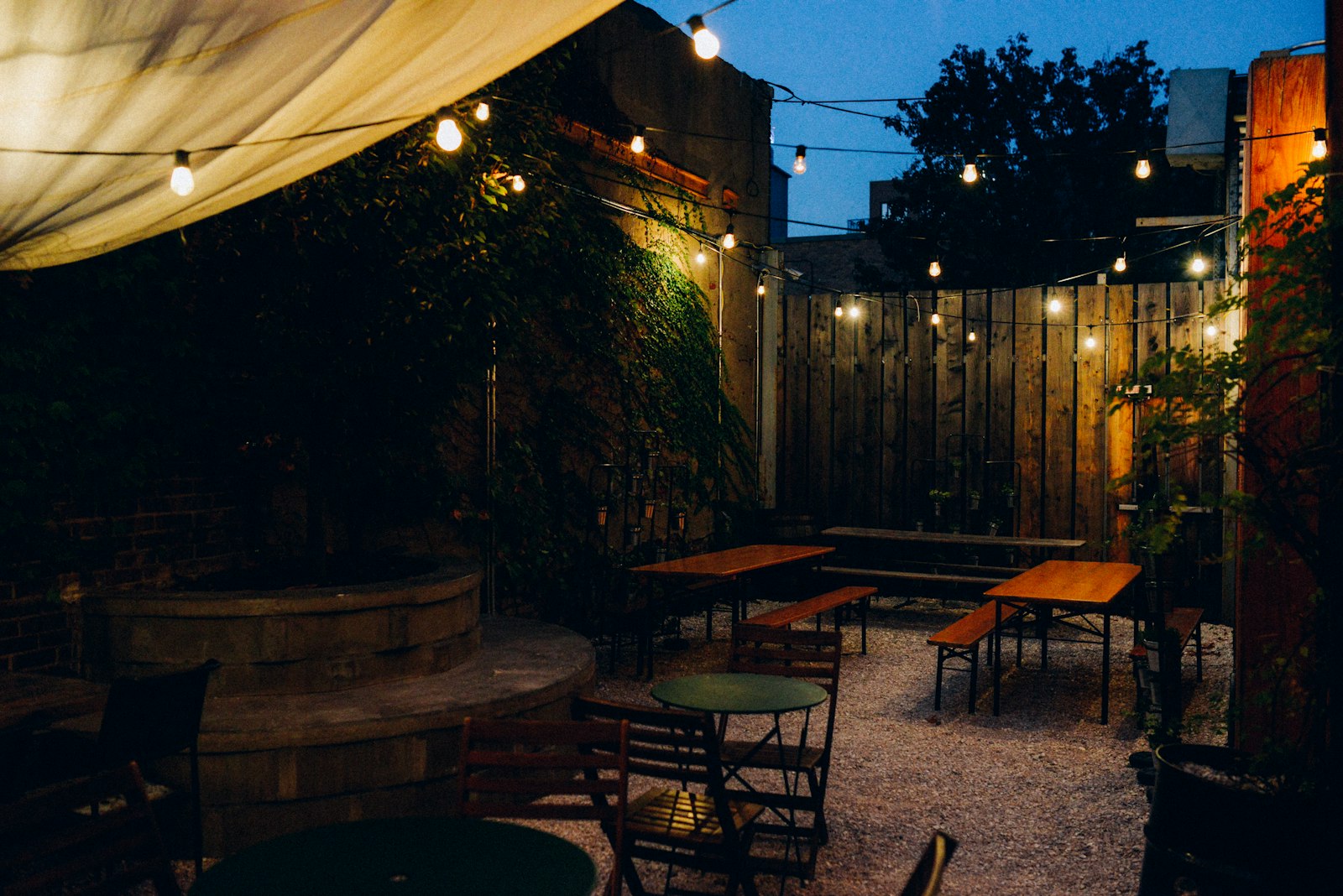 Outdoor seating at dusk under warm overhead light, the kind of evening use patio lighting has to support